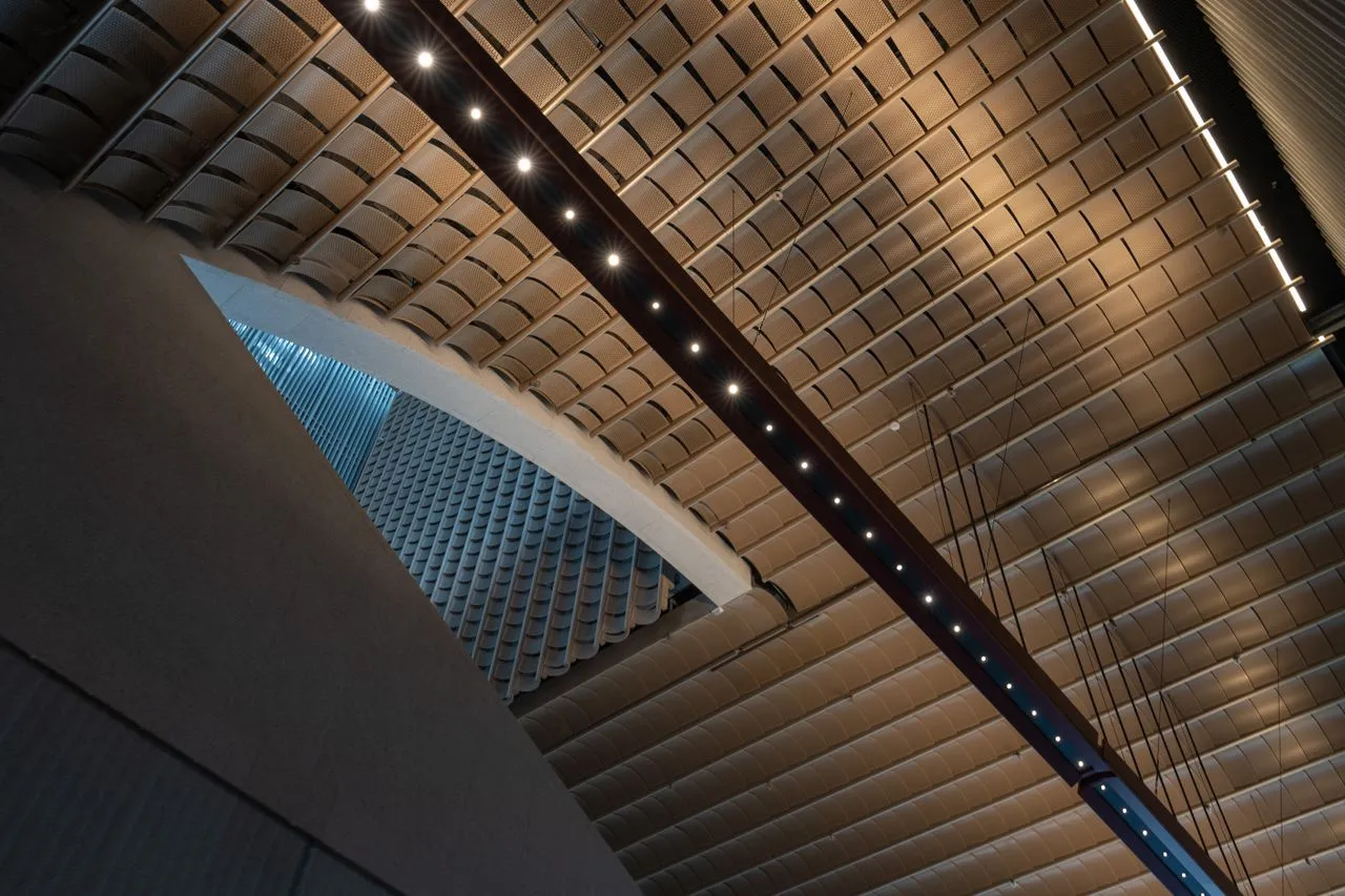 Geometric concrete arches beneath a patterned ceiling